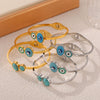 Wholesale Fashion Blue Eye Pattern Round Titanium Steel Goldplated Spring Bracelet Jewelry